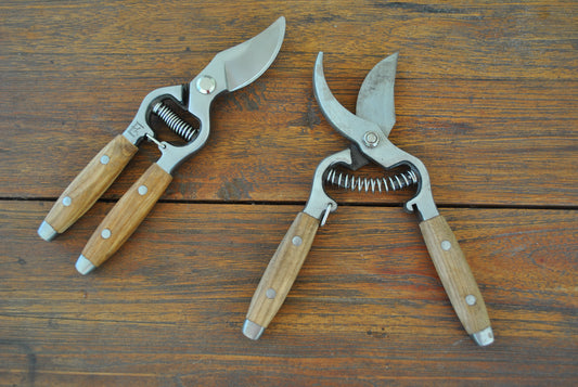 A couple pair of wooden handles secateurs. One open and one closed